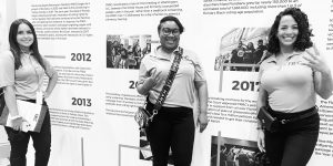 Three FRRC staff members pose in front of a display that illustrates the ten-year history of the Florida Rights Restoration Coalition during the organization’s annual Convening (Photo credit: FRRC).